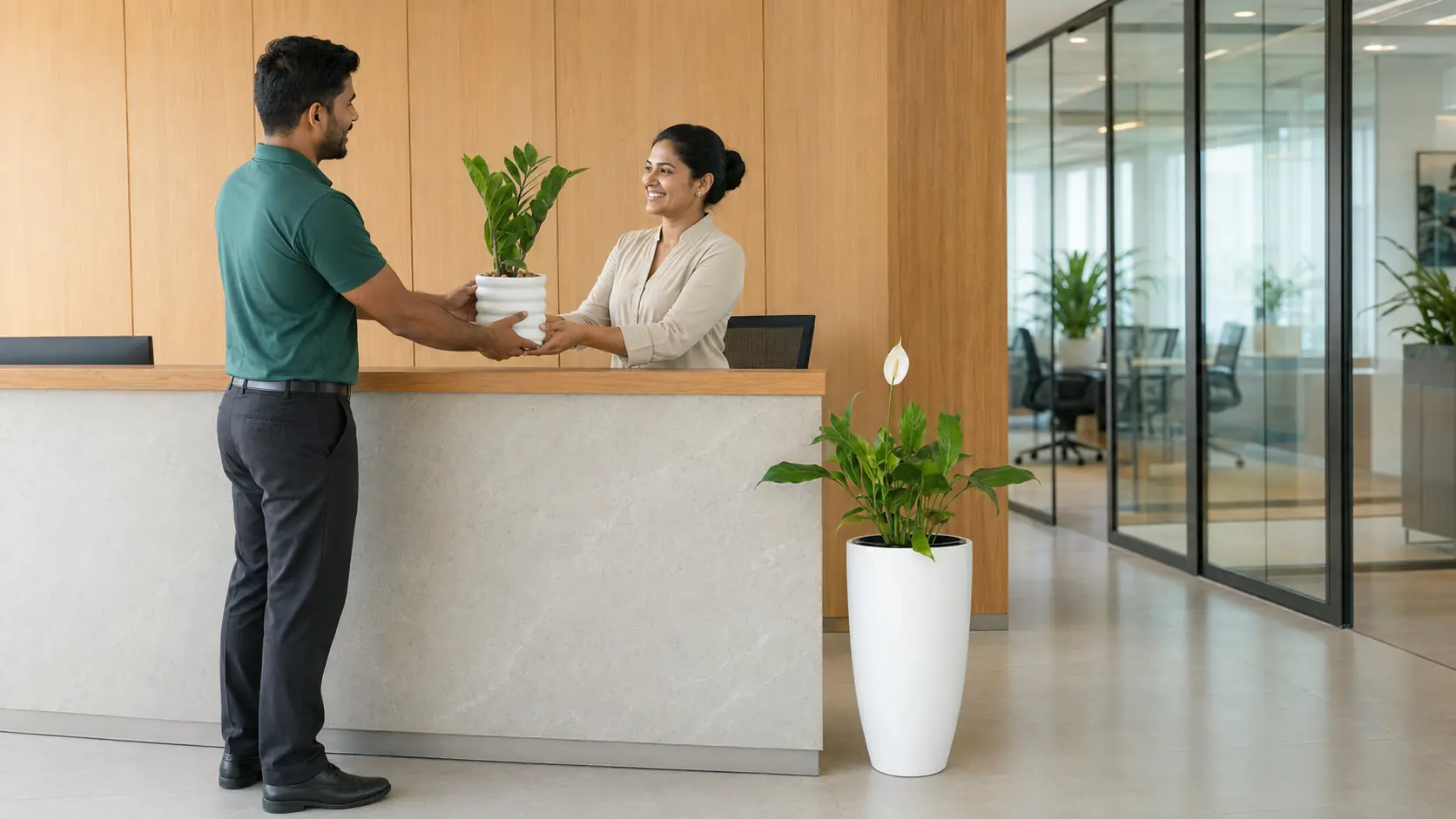 A PlantMe delivery team member handing a potted plant to a Colombo office receptionist